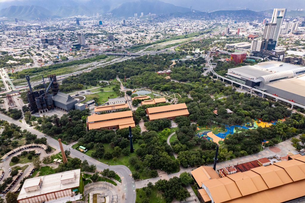 Vista aÃ©rea del parque con el alto horno de acero, naves de techo naranja y Ã¡rea de juegos infantiles